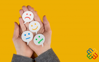 Una mano su sfondo giallo con dei post it rappresentati delle emoji